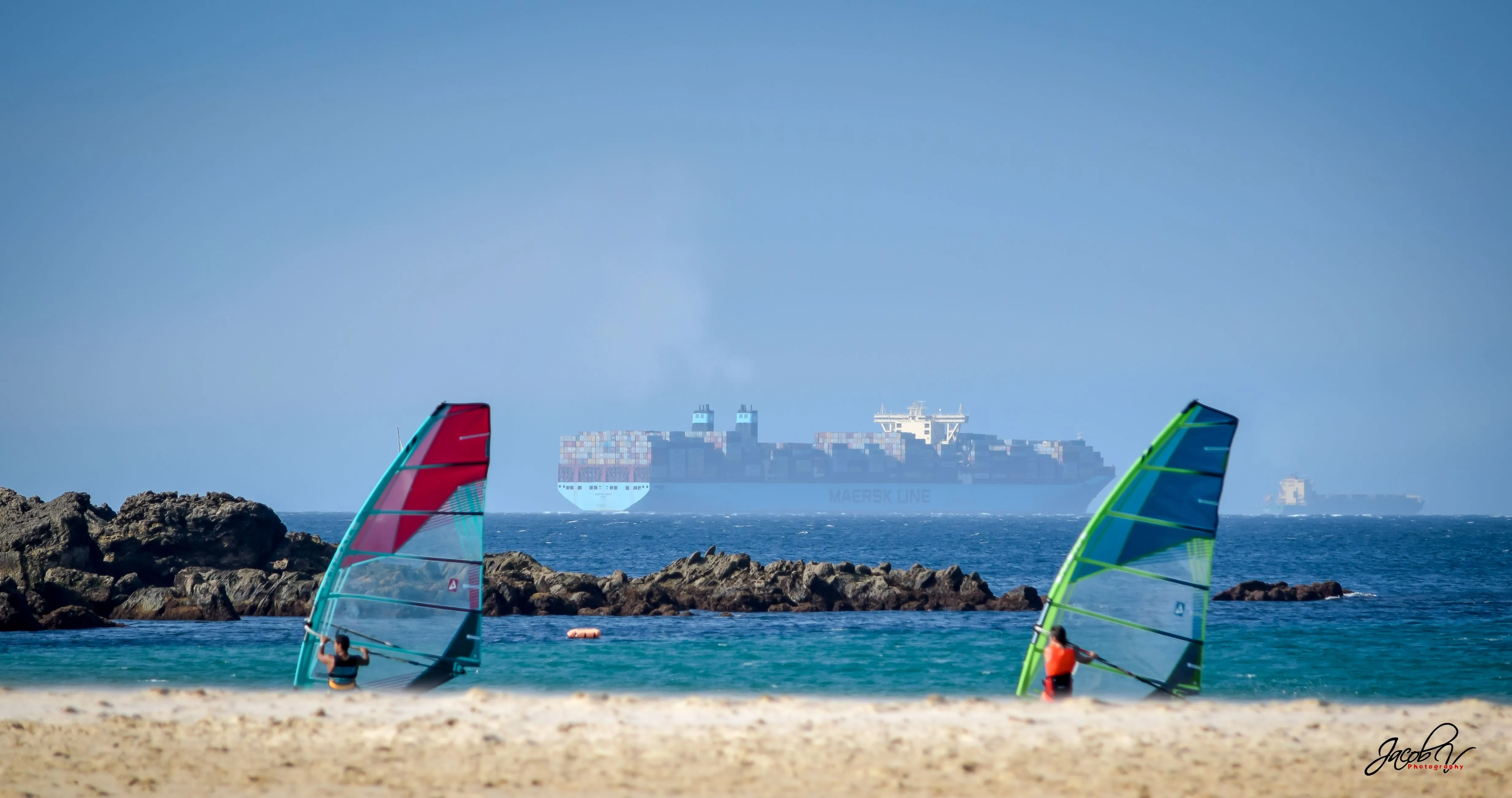 Windsurfers by the rocks with the Strait behind